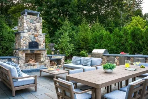 Summer garden party setting with an outdoor dining table surrounded by lush seasonal plantings and a well-maintained residential landscape.