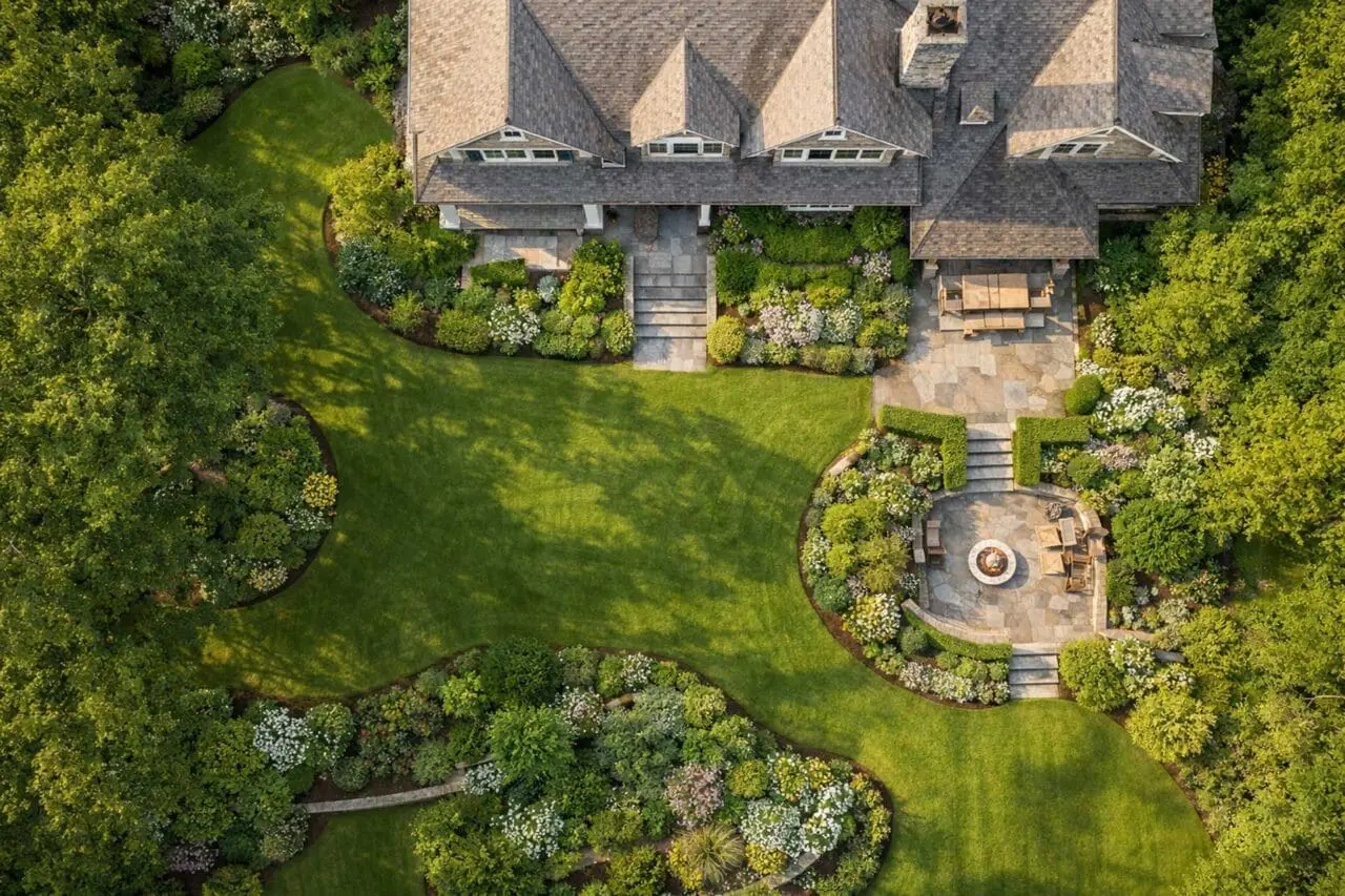 Aerial view of a lush New England estate landscape with layered planting, stone terraces, and timeless outdoor structure.