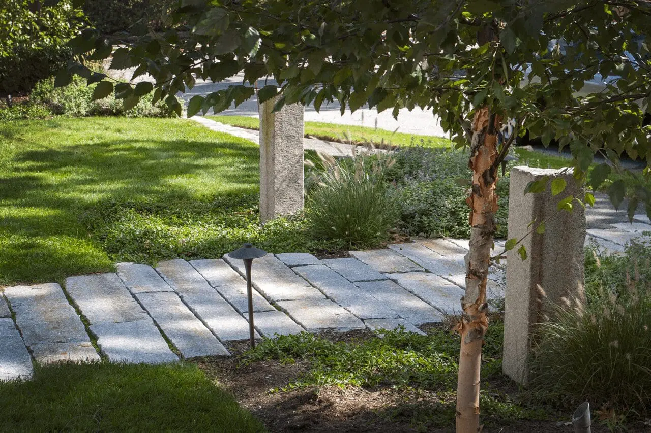 A gently curving stone path leads through layered garden plantings, showing how circulation can feel natural while still giving the landscape clear structure.