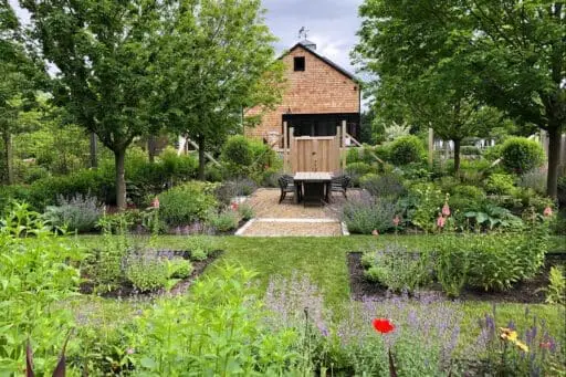 Carlisle, MA - A garden setting with native plantings surrounding a simple barn structure, creating a functional outdoor space that blends naturally with its surroundings.