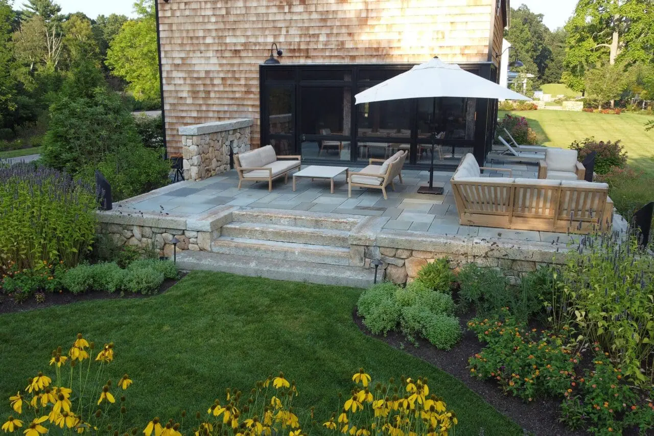 Carlisle, MA - A stone patio set within a sustainable landscape, combining natural materials and surrounding plantings to create a durable, low-maintenance outdoor space.