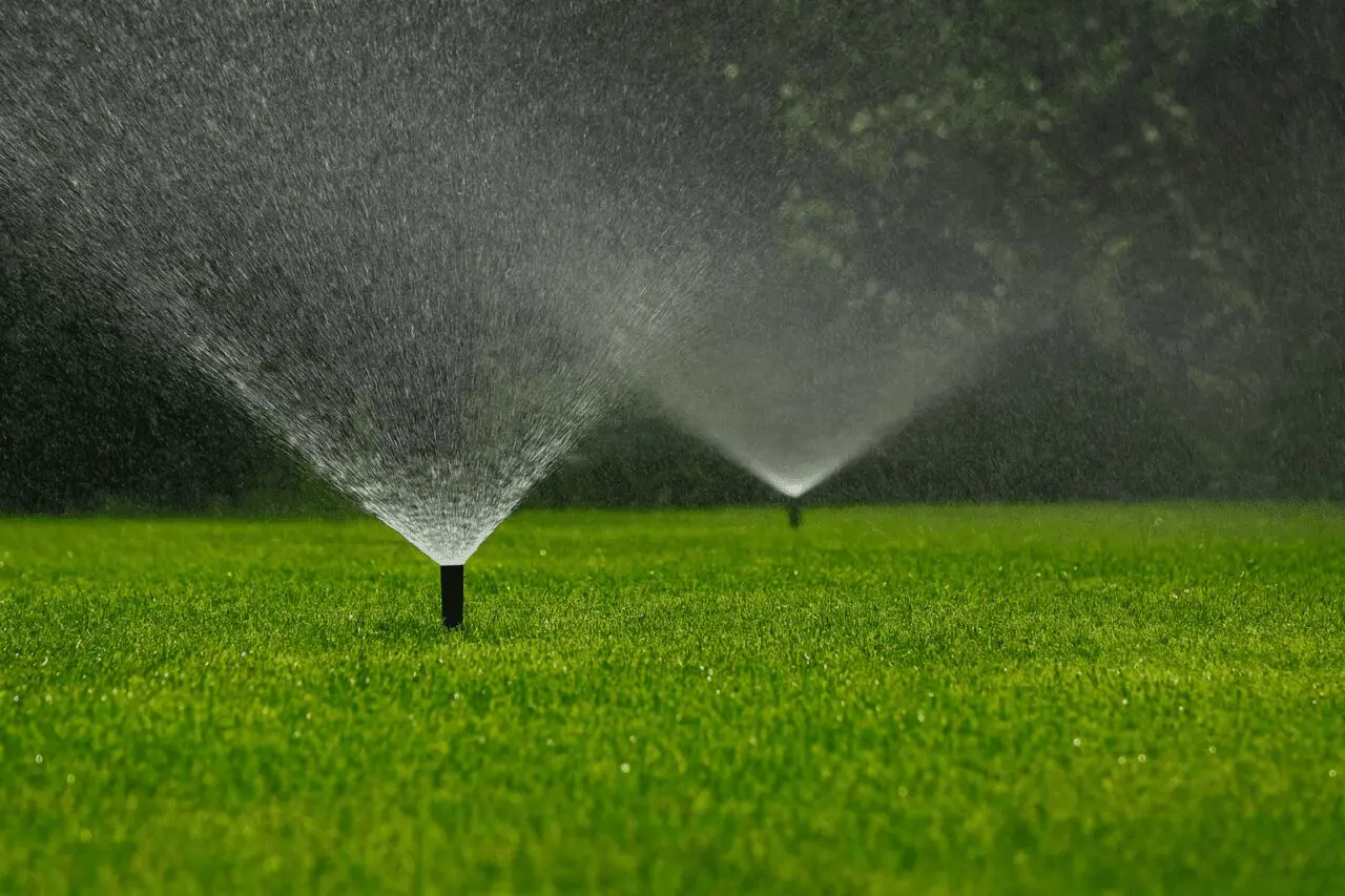 Lawn irrigation system with multiple sprinklers watering a healthy green landscape. abladeofgrass.com