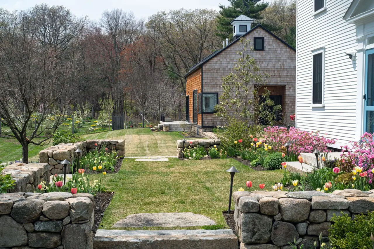 Carlisle, MA - A stone-lined path connects gardens to the barn, blending circulation with seasonal planting and historic context.