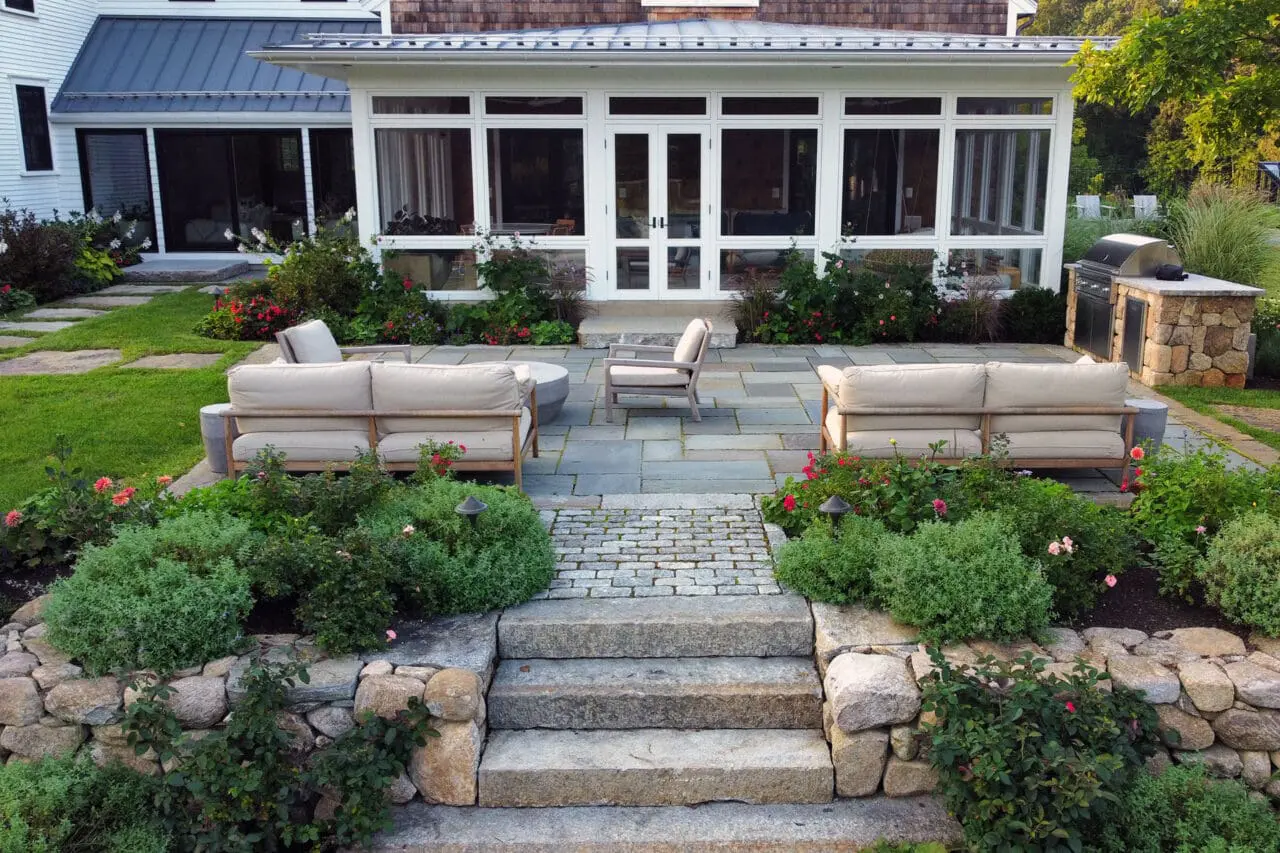 Carlisle, MA - A lower stone terrace offers an intimate outdoor lounge, defined by retaining walls that create privacy and visual depth.