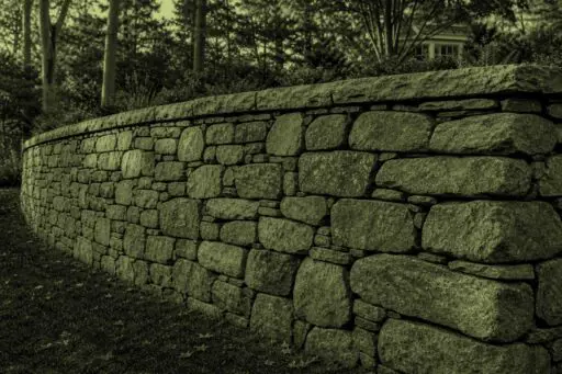 Acton, MA - A stone retaining wall leans outward, indicating movement and possible structural failure.