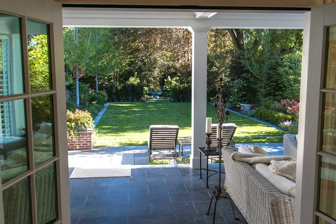 Belmont, MA - The multi-seasonal porch leads to a bluestone patio abutting lush gardens and lawn.