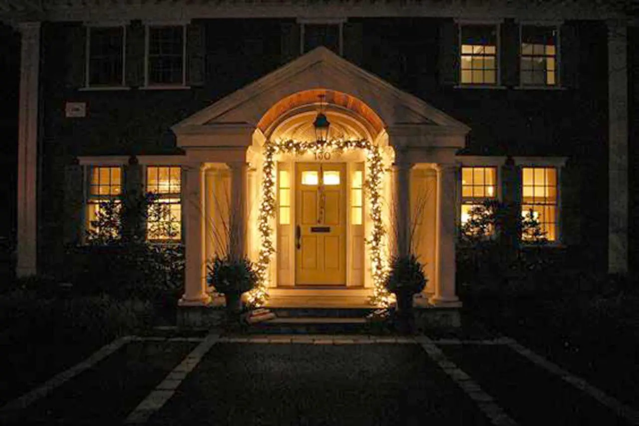 A lit garland around the main entrance and seasonal greens in the urns provide elegant holiday appeal.