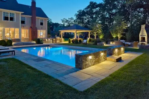 Wilmington, MA - Landscape lighting adds warmth, depth, and definition, making the pool, stonework, and surrounding trees more inviting after dark.