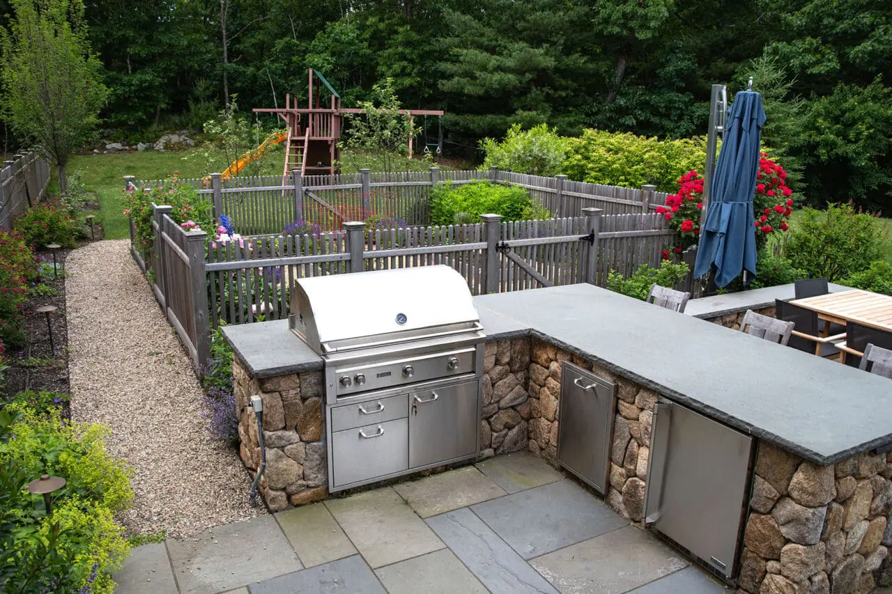 Stone-built outdoor cooking and dining space with integrated grill and fire elements, designed to support entertaining and comfortable outdoor meals.