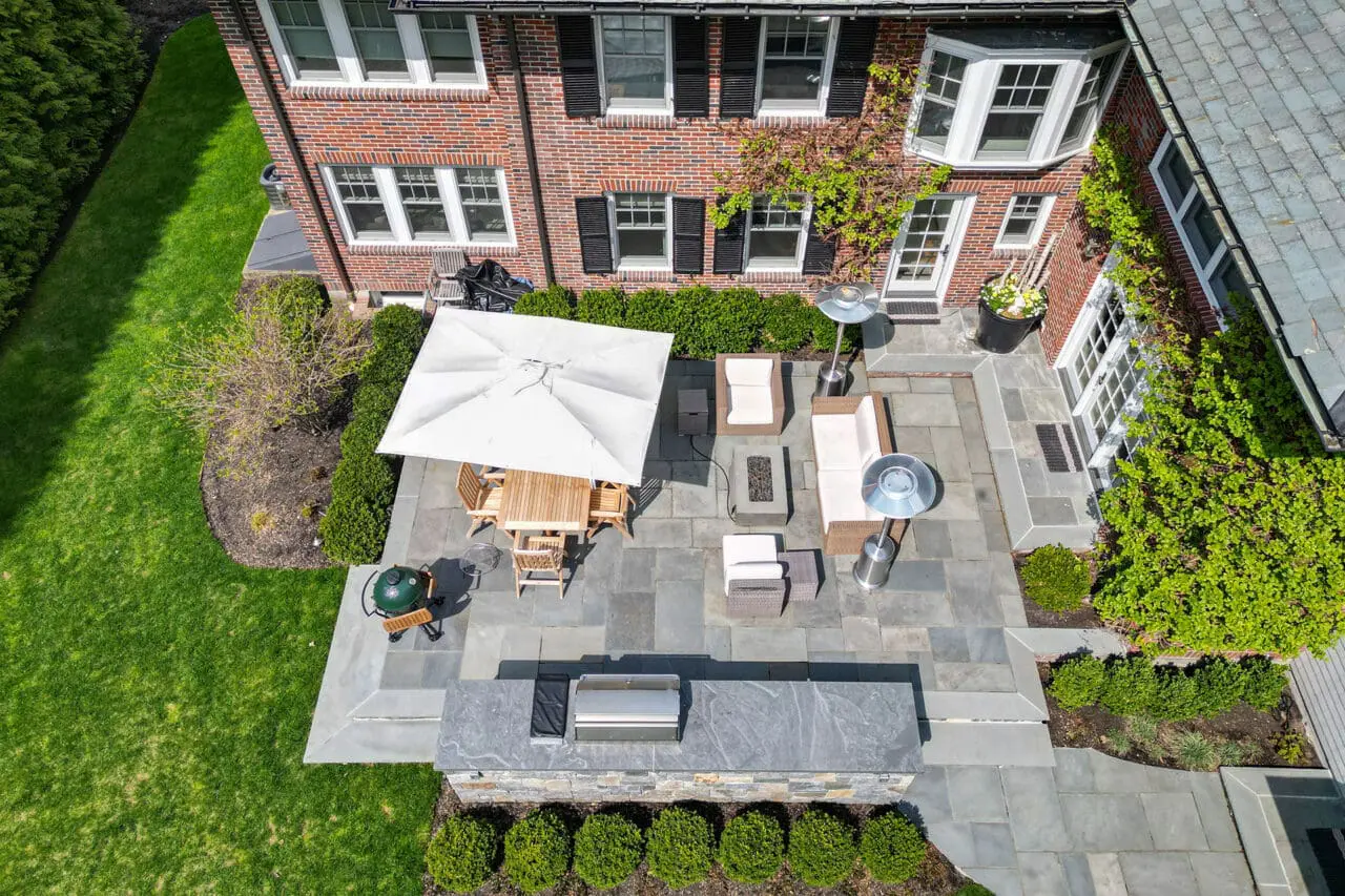 Compact city patio with outdoor kitchen and firepit integrates functional amenities into tight outdoor space for social cooking and lounging.