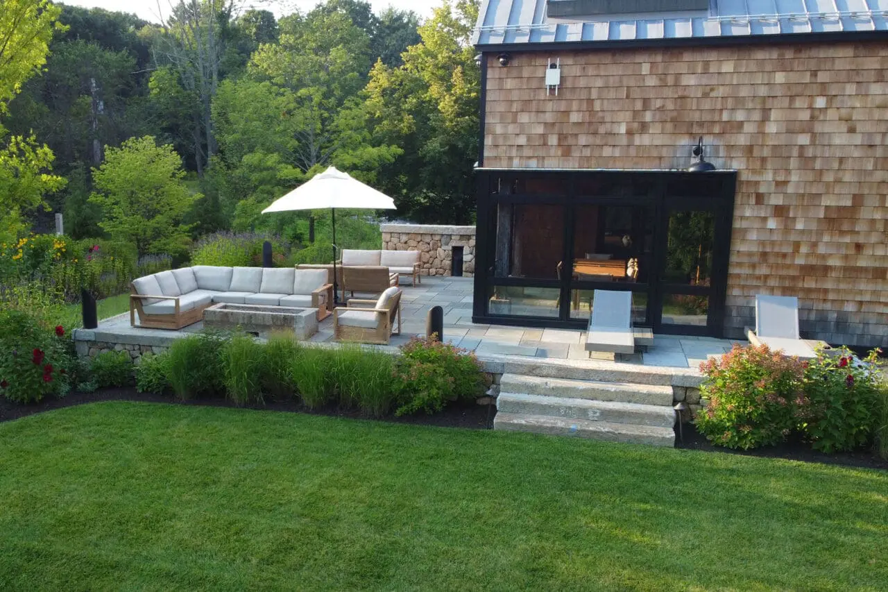 Carlisle, MA - Outdoor lounge terrace with firepit set within a stone surround invites cozy evenings and social gatherings in Newburyport’s scenic outdoor settings.