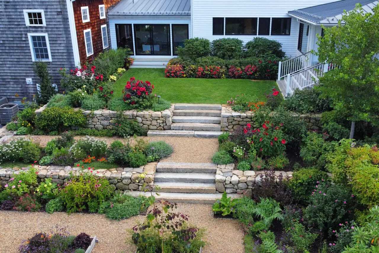 Carlisle, MA - Fieldstone walls and granite steps step through a tiered garden, using shrubs and hedges to visually connect each level and create continuity.