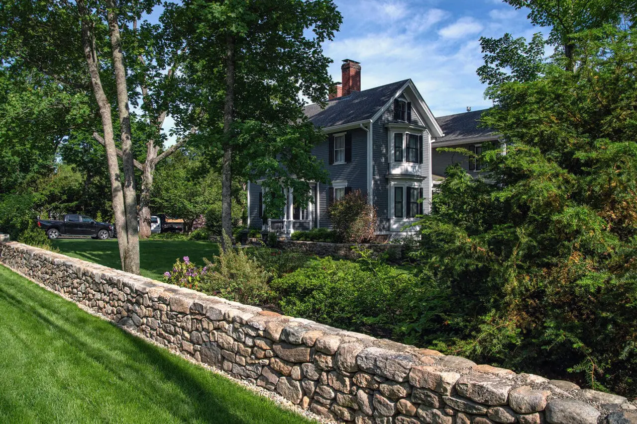 Concord, MA - This front-yard fieldstone wall reinforces the traditional character of the home, with layered shrubs and hedges providing structure and curb appeal.