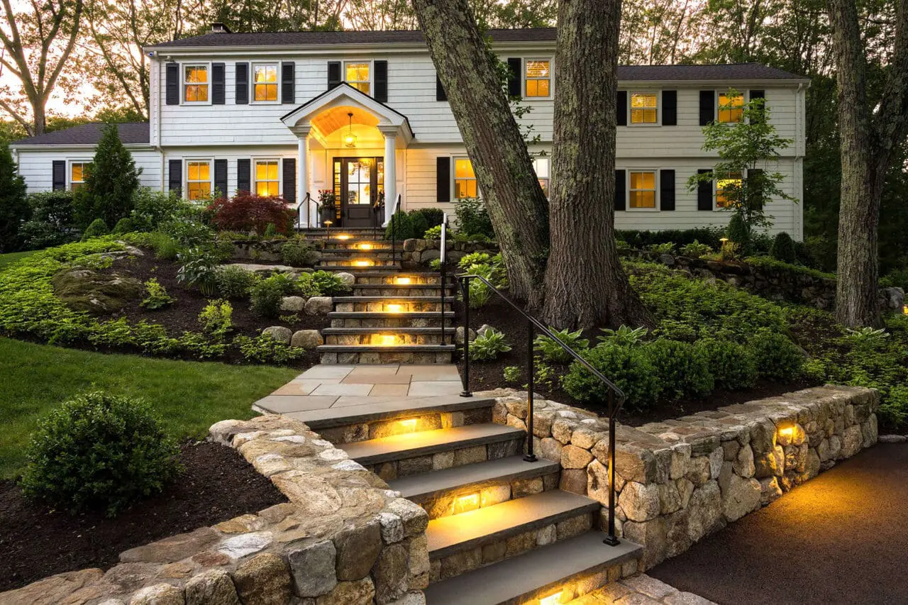 Newton, MA - Illuminated stone steps climb a hillside approach, combining safety and visual appeal while adjacent shrubs and hedges frame the path and enhance nighttime presence.