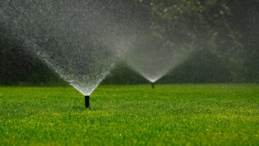 Lawn irrigation system with multiple sprinklers watering a healthy green landscape. abladeofgrass.com