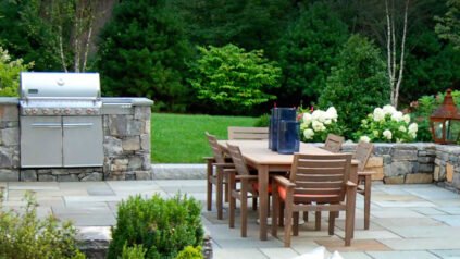 A thoughtfully designed outdoor dining area creates a comfortable place for meals and entertaining, with well-planned seating, circulation, lighting, and surrounding plantings helping the space feel connected to the landscape.