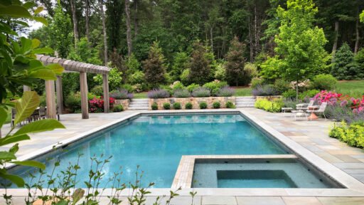 Elegant Boston-area landscape featuring a stone patio, mature plantings, and refined outdoor living details that reflect the investment involved in high-end landscape design.