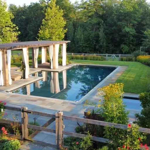 Carlisle, MA - A pool landscape blends a cedar pergola, meadow-edge planting, and refined outdoor living design for a relaxed New England backyard retreat.