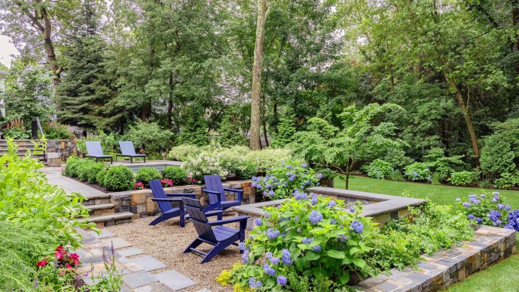 Wellesley, MA - This gravel fire pit terrace is softened by hydrangeas and layered planting, offering a relaxed gathering space set slightly apart from the pool. photo credit: Michael J Lee