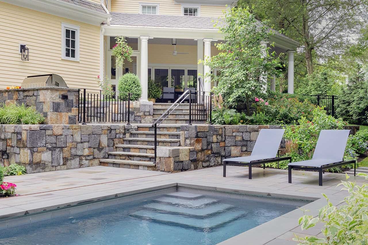 Wellesley, MA - A compact pool, terraced stone walls, and a screened porch work together to create a cohesive outdoor living landscape on a challenging sloped site. photo credit: Michael J Lee