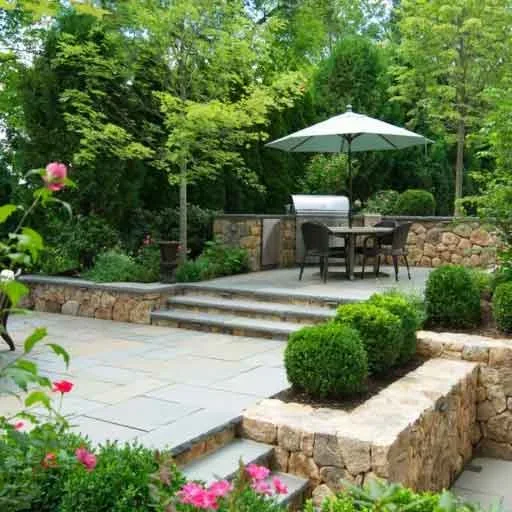 Wellesley, MA - A bluestone patio and terrace design uses masonry steps, layered grade changes, and elegant planting to connect the home and garden.