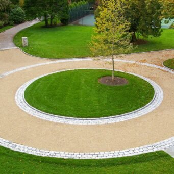 Duxbury, MA - This circular gravel driveway features a cobblestone ring and planted center island, organizing traffic flow while adding visual focus and texture.