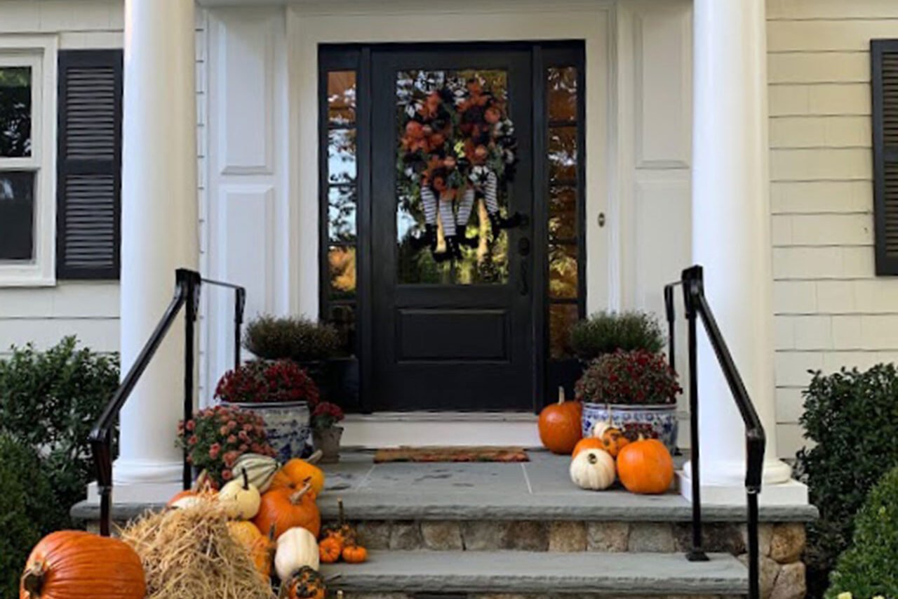 Stone steps lined with pumpkins and hay bales enhance a formal entry, adding seasonal warmth while respecting the Wellesley, MA home’s classic architecture.