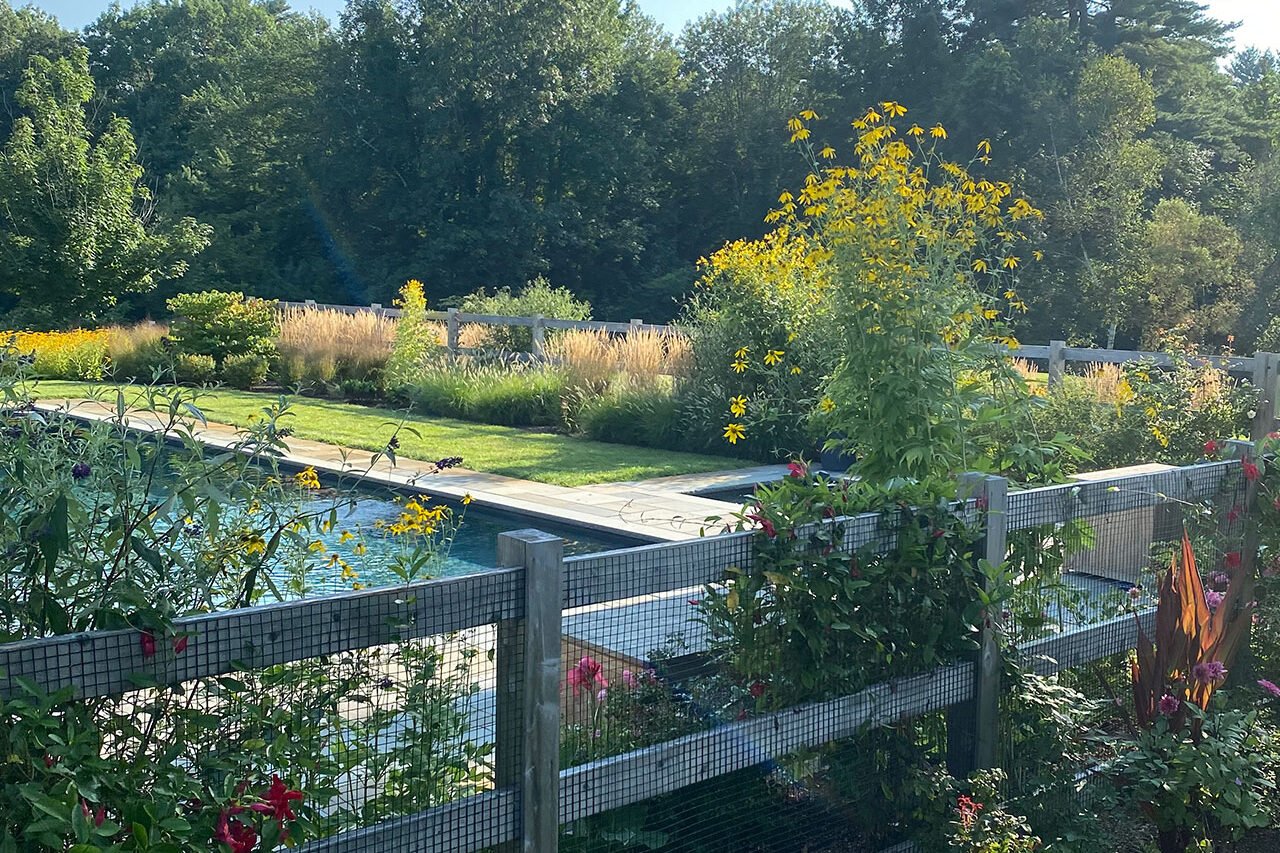 Wire panel fencing with wood posts defines garden edges while keeping views open, protecting plantings without closing in the landscape.