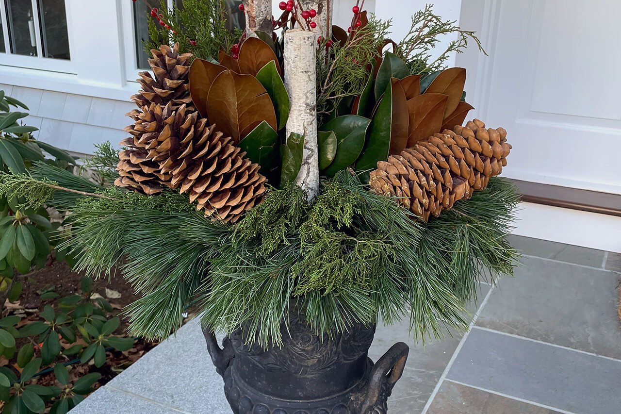 A cast planter anchors the front entryway with a winter charm feel, using soft, mixed plantings to add warmth and structure while offering an easy container that transitions seasonally.
