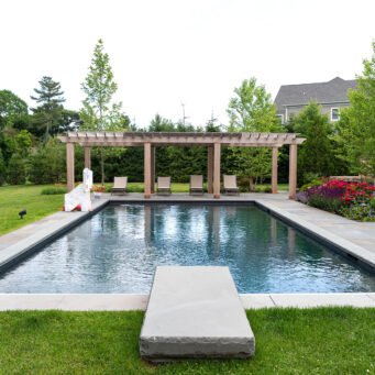 A geometric pool paired with a linear pergola and bluestone terrace, reinforcing modern design principles through repetition, structure, and clean transitions.