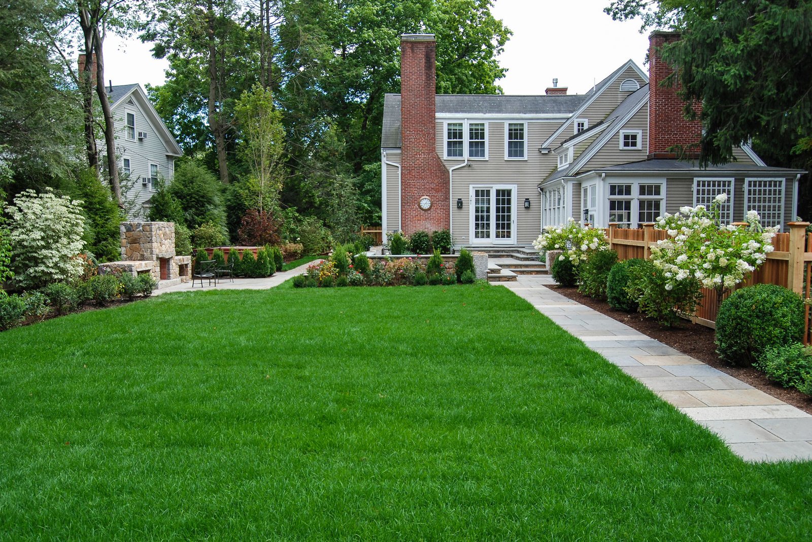 Newton backyard with lawn, stone path, and outdoor fireplace