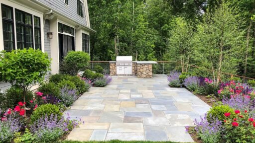 Lincoln, MA - After the transformation, this Weston patio becomes a polished outdoor living space with refined stonework, comfortable furnishings, and layered planting that gives the area structure and privacy.