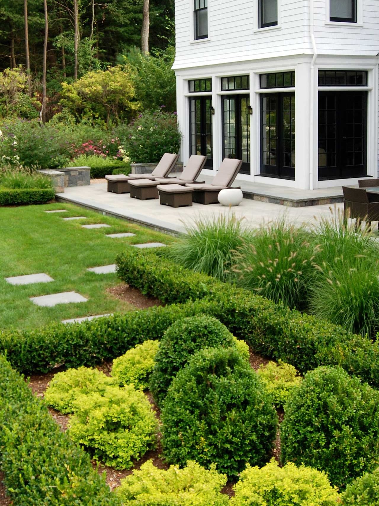 Weston, MA - A stone patio in Weston is framed by a neatly clipped hedge and comfortable outdoor furniture, creating a defined, private space for relaxing and entertaining.
