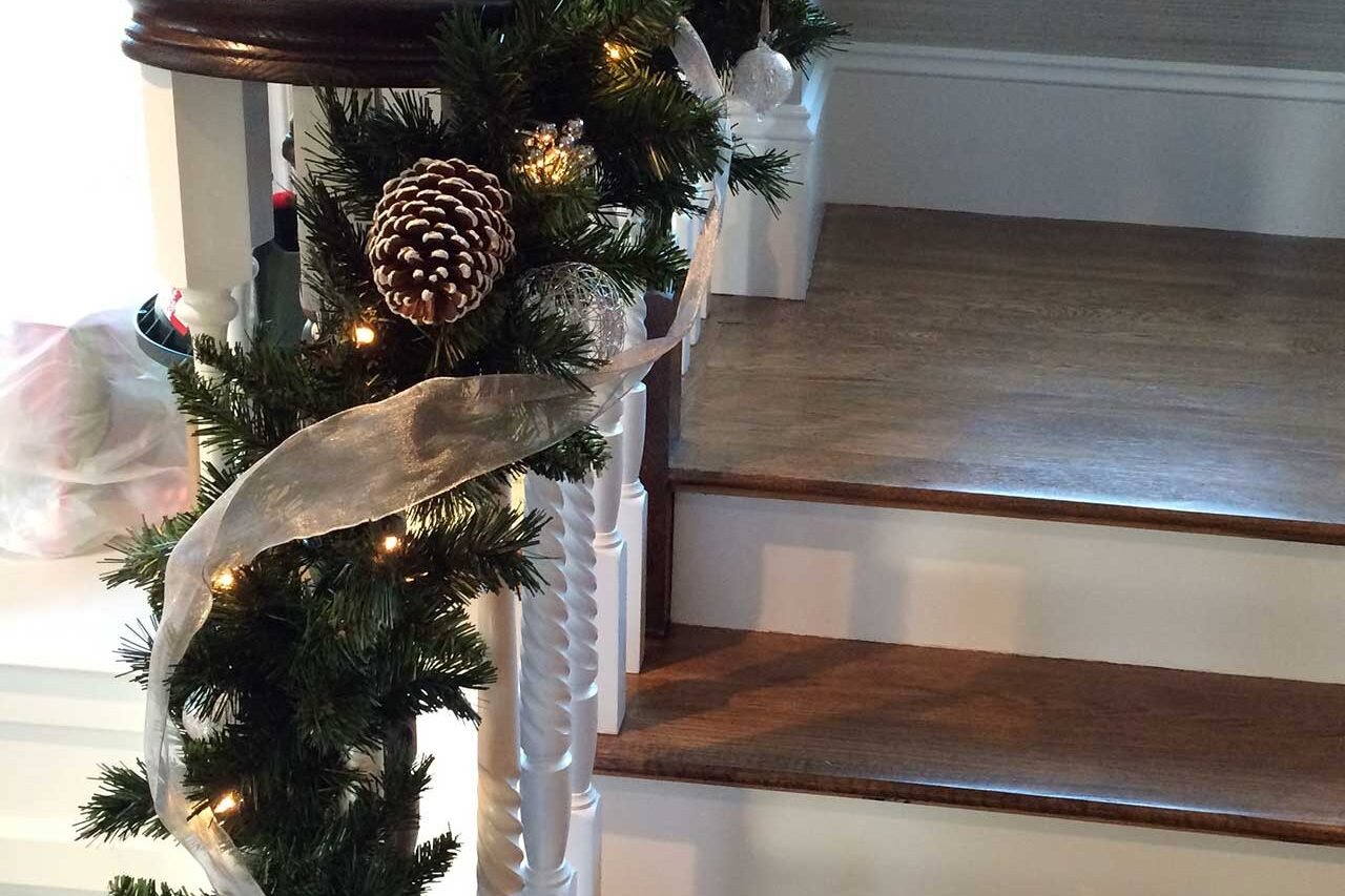 Indoor staircase bannister decorated with pine garland and simple evergreen holiday greenery.