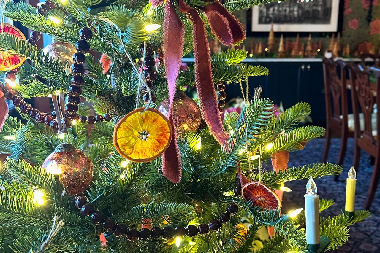 A thoughtfully styled indoor Christmas tree with natural accents and warm lighting says winter décor with understated charm.